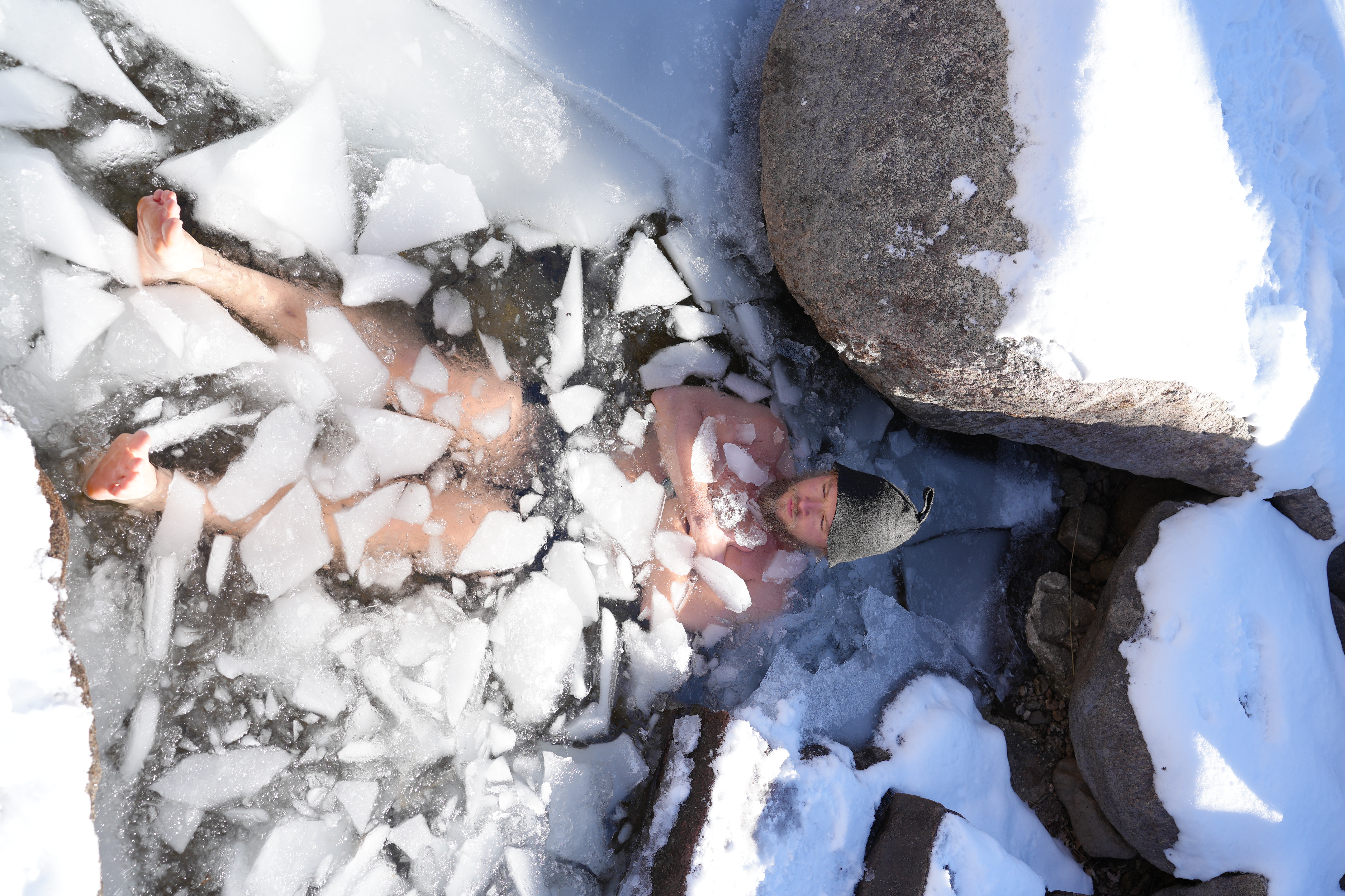 Man submerged in snowy ice plunge, peaceful expression